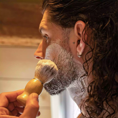 Scheerkwast tegen de wang van een man.